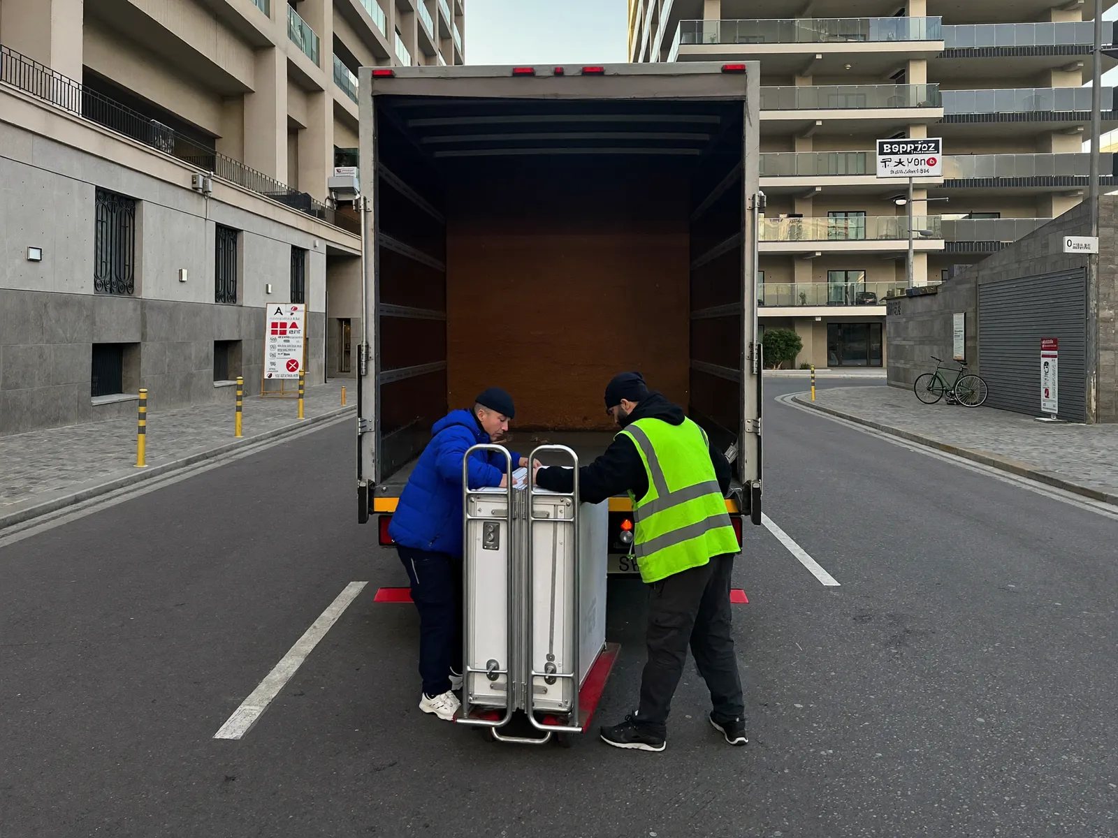 Moving crew loading furniture into a closed box truck at a building loading bay